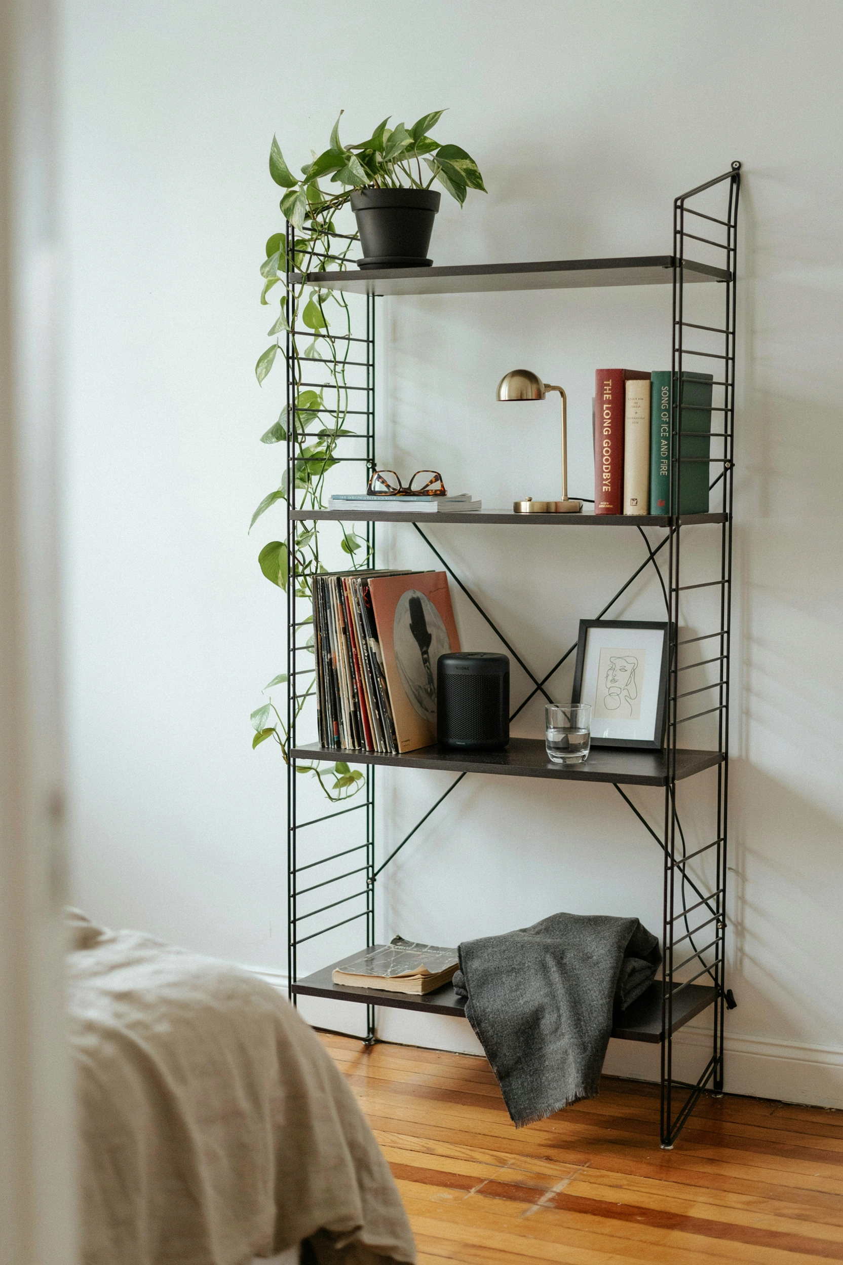 Black metal open shelving as storage and room divider in a college apartment bedroom for men