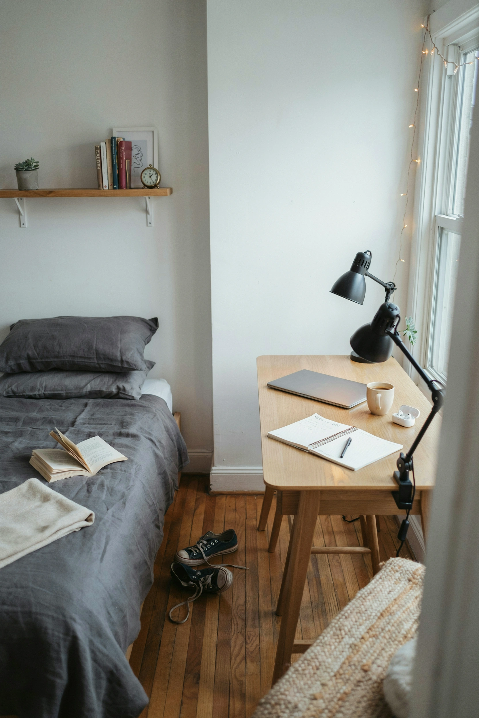 Charcoal grey bedding with warm wood shelf and desk lamp — minimalist college bedroom decor ideas for men